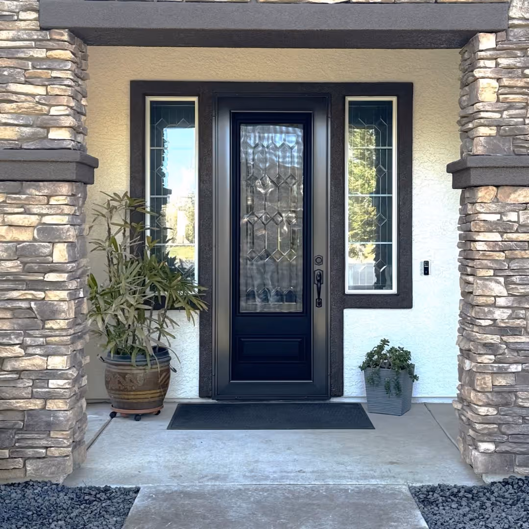 Dark bronze custom security screen door over a black entry door with decorative leaded glass