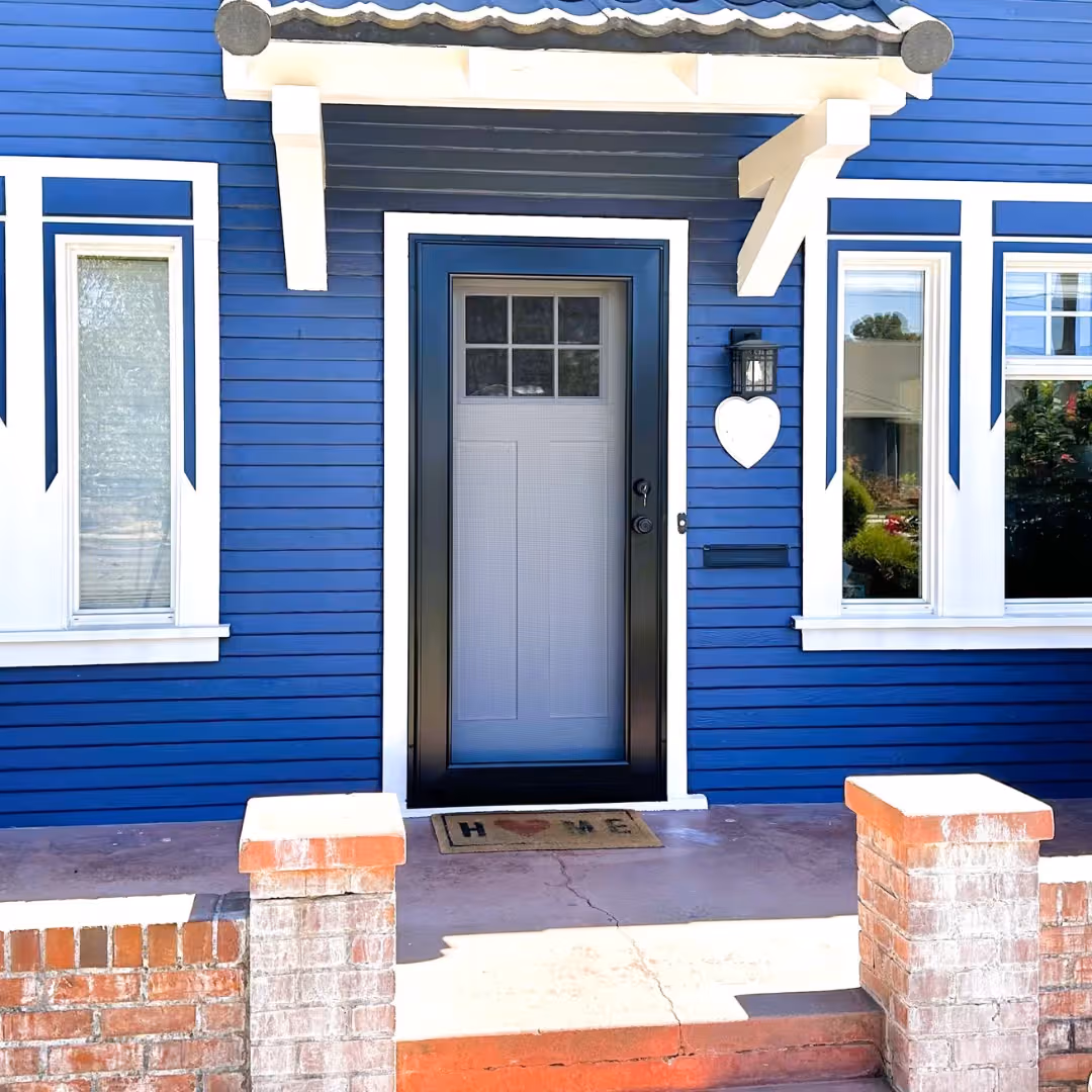 Black custom security screen door on the front entry of a blue craftsman-style home