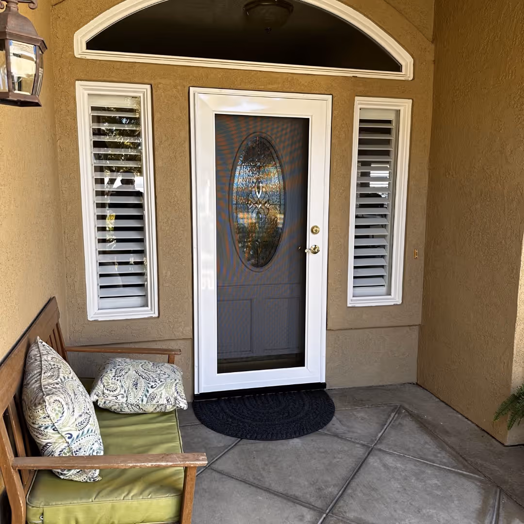 White custom security screen door over an entry door with an oval leaded-glass insert and sidelights