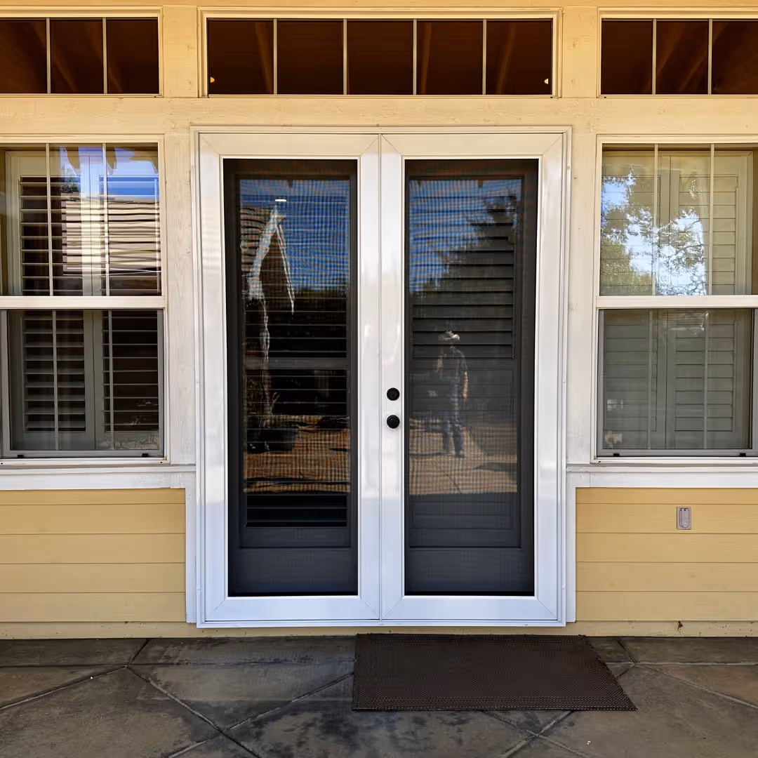 White custom security screen doors installed over a pair of French patio doors