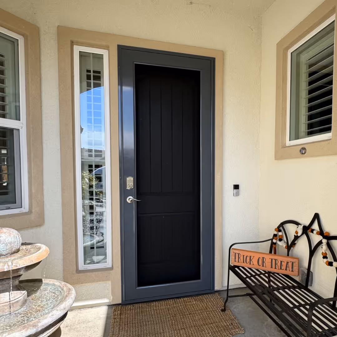 Charcoal grey-blue custom security screen door on a stucco home entry