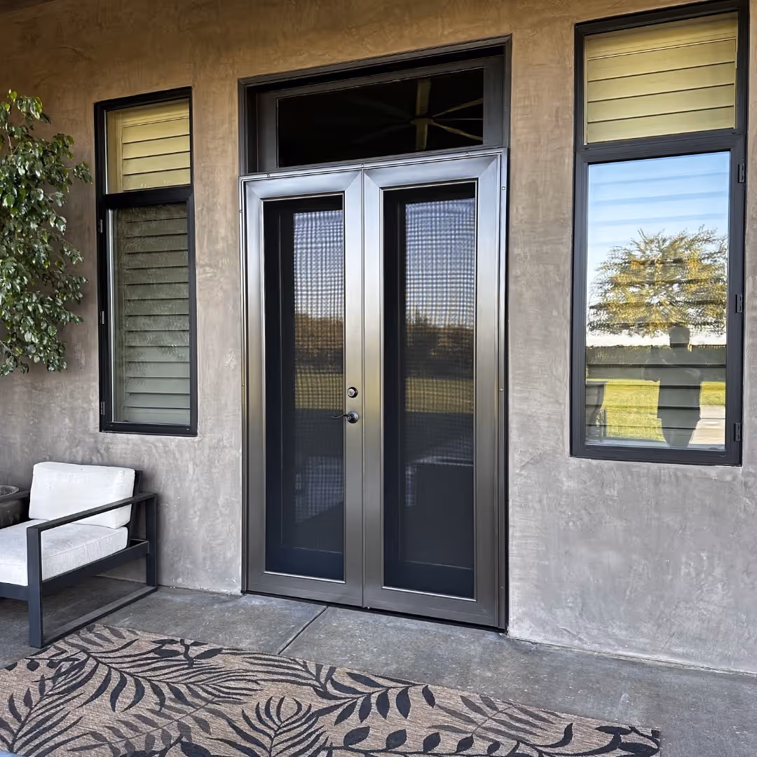 Grey custom security screen doors installed over French patio doors with a transom window above