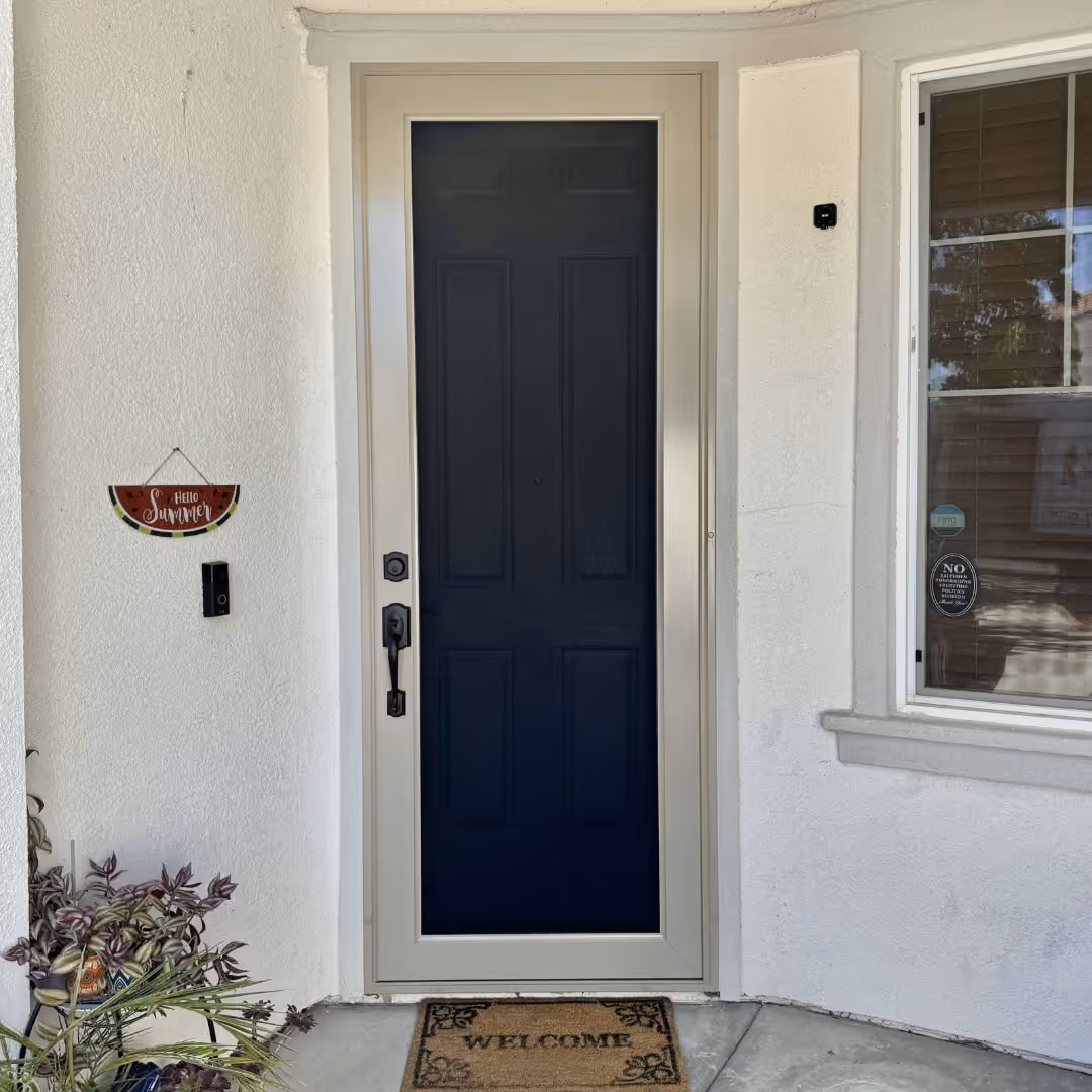 White custom security screen door over a navy entry door on a white stucco home
